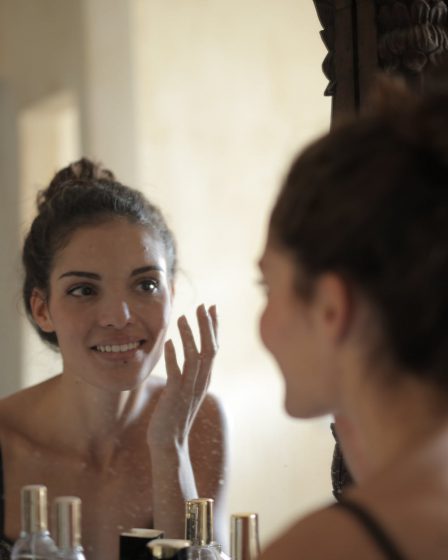 Kobieta po zabiegu medycyny estetycznej stoi przed lustrem