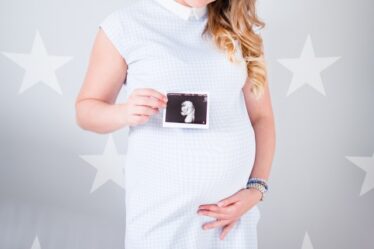 Kobieta w ciąży trzyma w dłoni USG