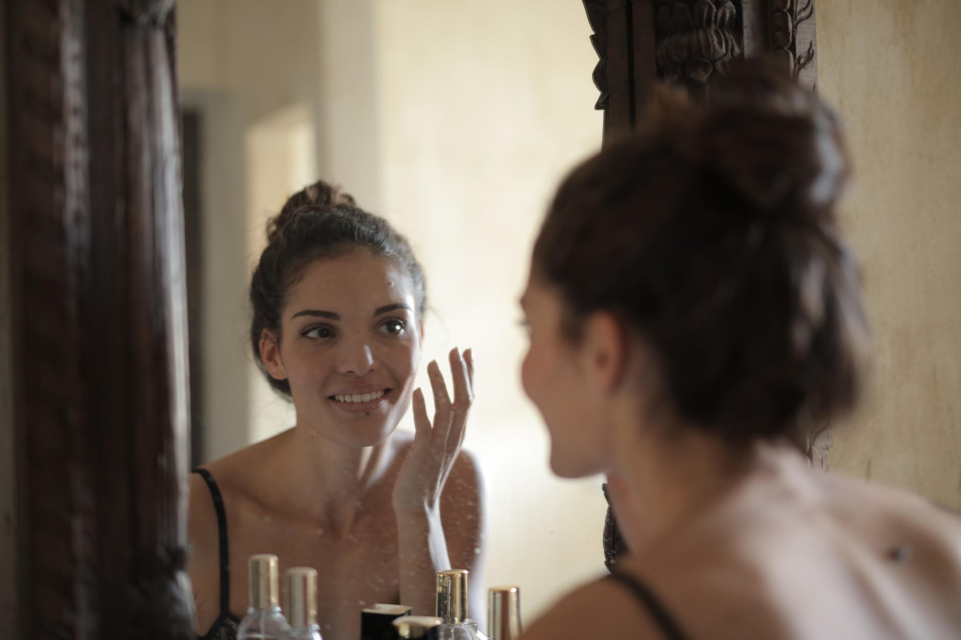 Kobieta po zabiegu medycyny estetycznej stoi przed lustrem