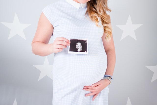 Kobieta w ciąży trzyma w dłoni USG